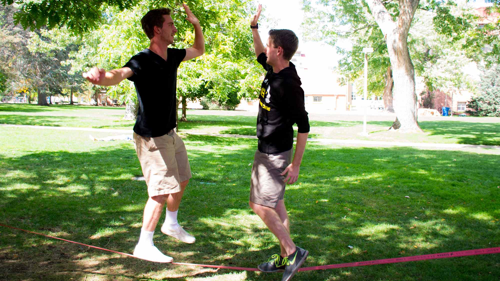 Two students high-fiving on a slack line